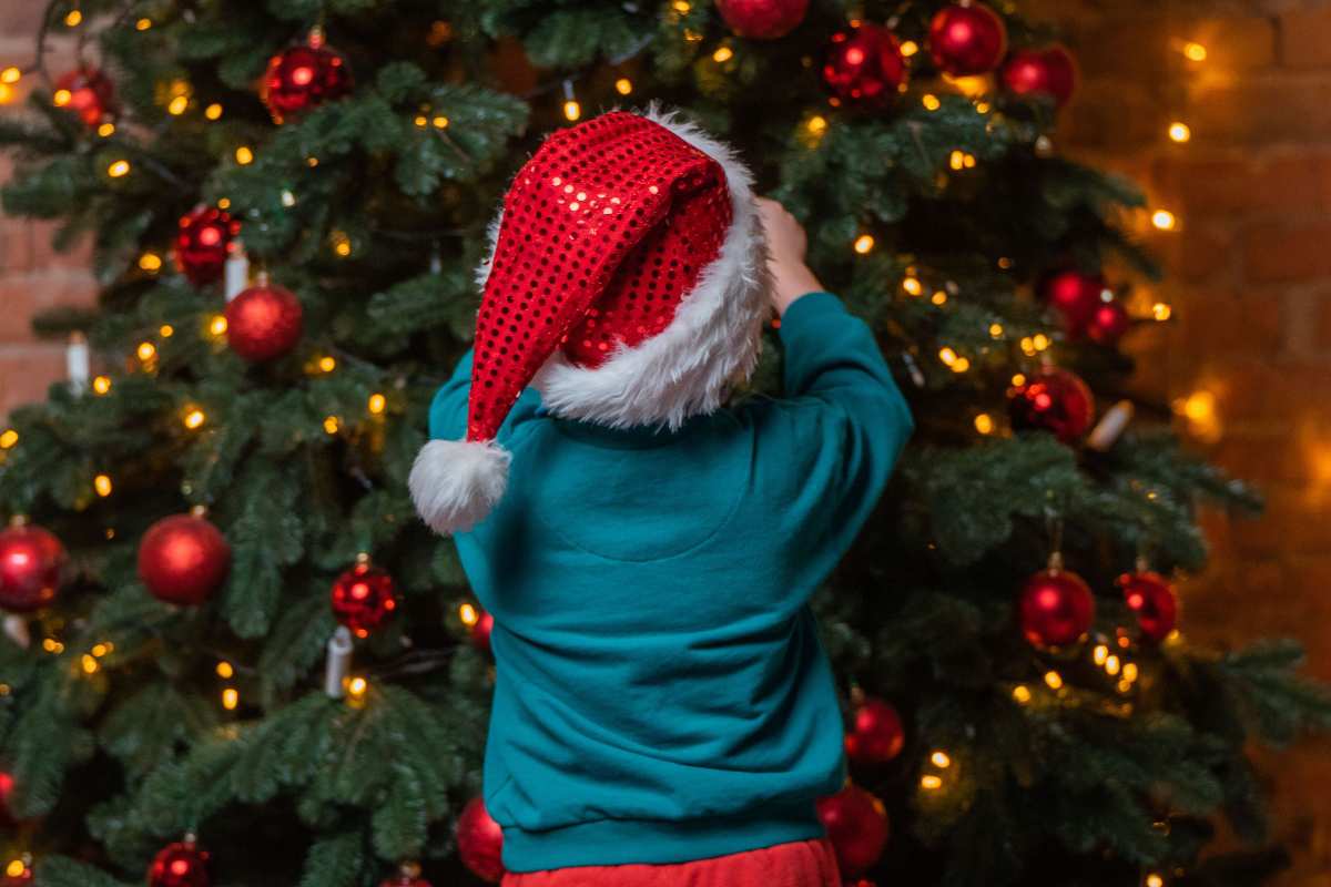 Bambino decora l'albero di Natale