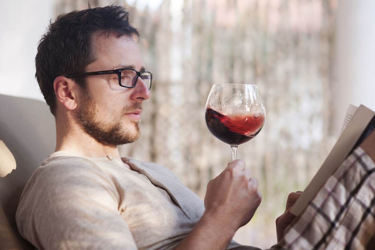 Ragazzo bene un calice di vino mentre legge